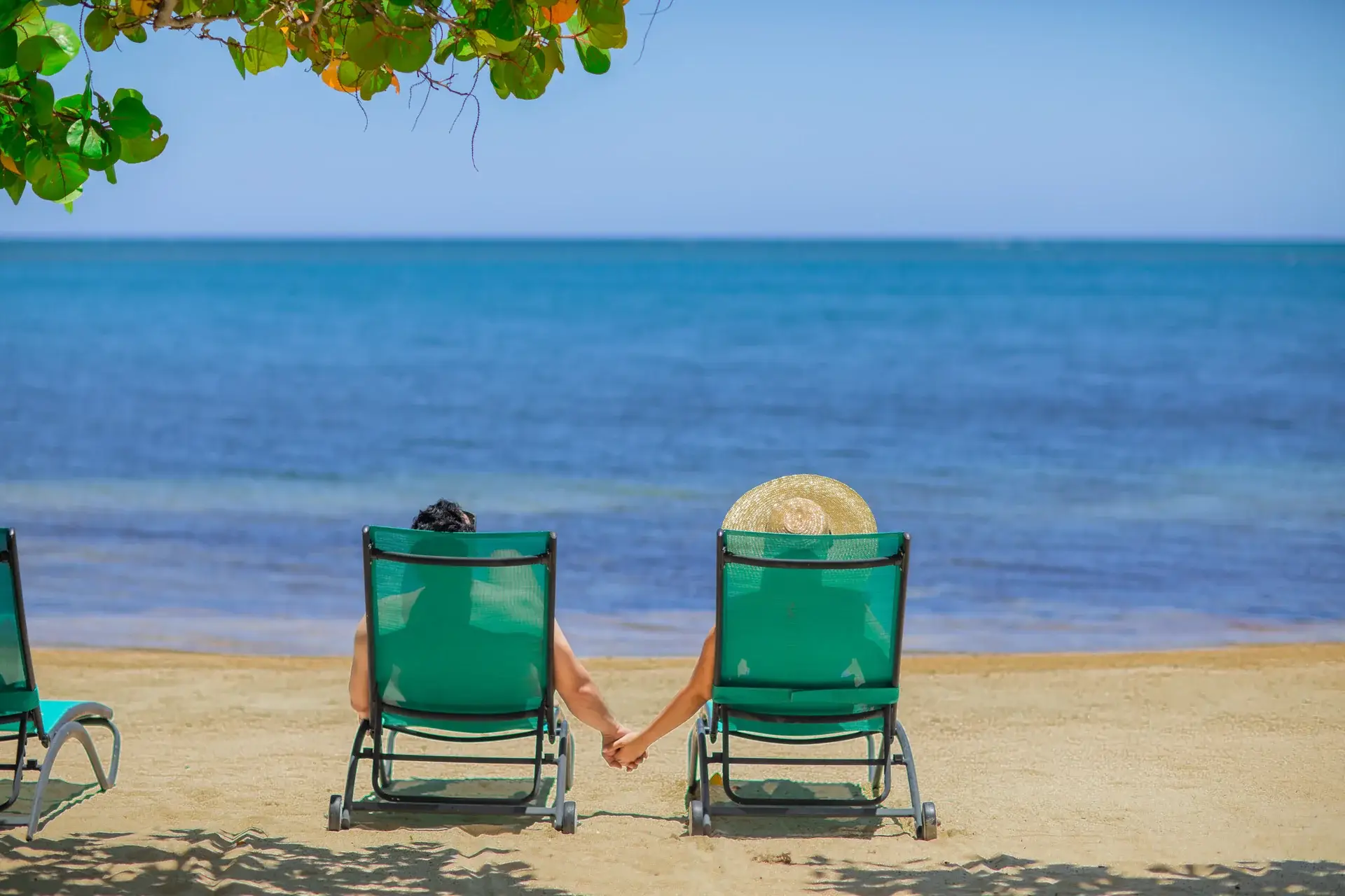 Couple relaxing in beach chairs beside the Caribbean at Pristine Bay